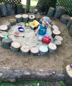 Child playing in a woodwares playscape sandbox with excess wood from Town Branch Tree Experts
